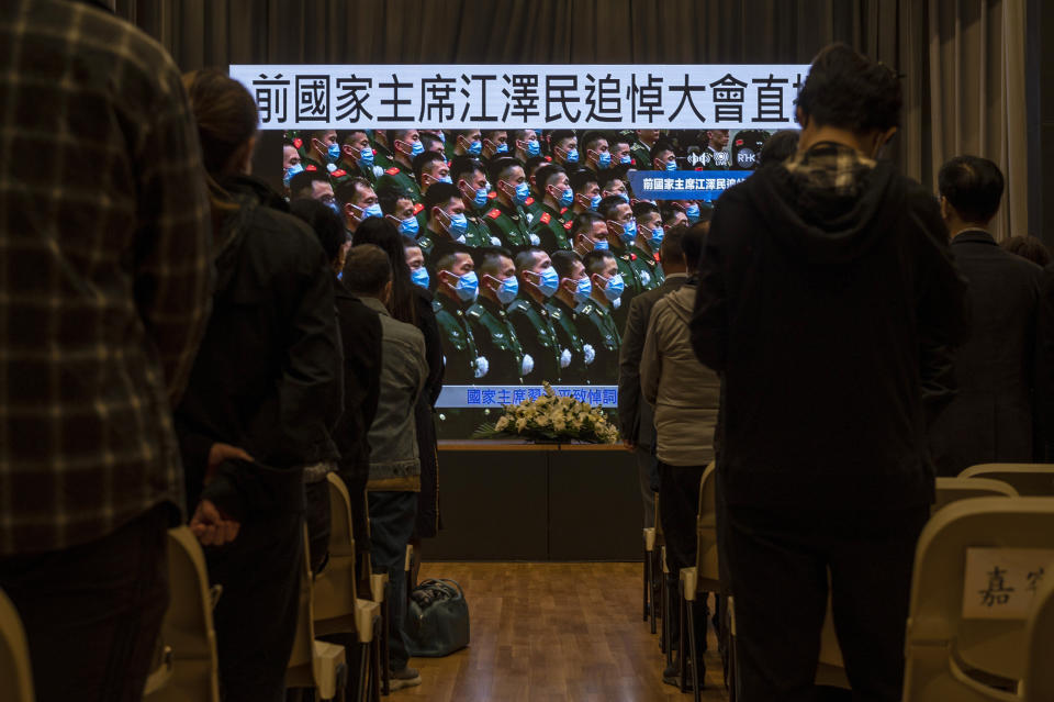 Residents watch a live broadcast of the memorial service for late former Chinese President Jiang Zemin on a screen at a community center in Hong Kong, Tuesday, Dec. 6, 2022. A formal memorial service was held Tuesday at the Great Hall of the People, the seat of the ceremonial legislature in the center of Beijing. Words on screen read "Former Chairman Jiang Zemin memorial live broadcast." (AP Photo/Vernon Yuen)