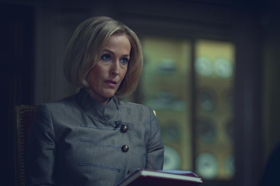 a woman (Gillian Anderson as Emily Maitlis), sitting down and holding a notebook, in the netflix movie 'scoop'