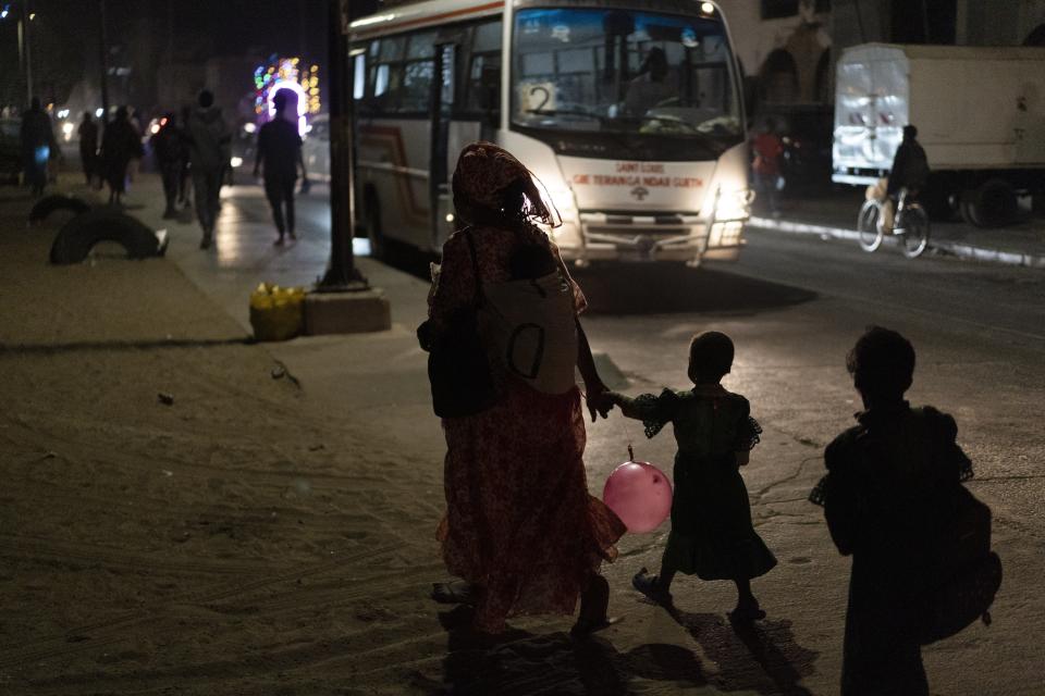 A woman holds the hand of a child as they walk on a street in Saint Louis, Senegal, Friday, Jan. 20, 2023. Officials promised the drilling in the area would soon bring thousands of jobs and diversification of the economy. Instead, residents say, the rig has brought only a wave of problems, unemployment and more poverty. (AP Photo/Leo Correa)