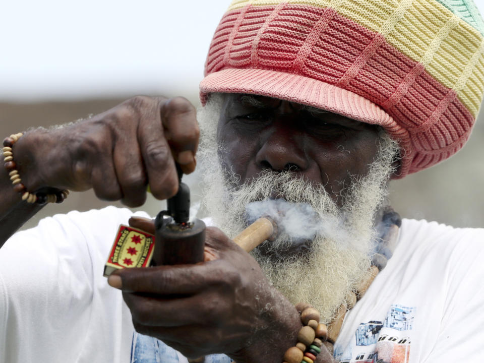 A spectator lights his pipe during day four of the first Test cricket match between India and West Indies at the Sir Vivian Richards cricket ground in North Sound, Antigua and Barbuda, Sunday, Aug. 25, 2019. (AP Photo/Ricardo Mazalan)
