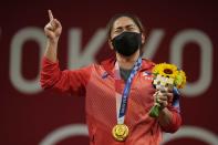 Hidilyn Diaz of Philippines celebrates on the podium after winning the gold medal in the women's 55kg weightlifting event, at the 2020 Summer Olympics, Monday, July 26, 2021, in Tokyo, Japan. (AP Photo/Luca Bruno)