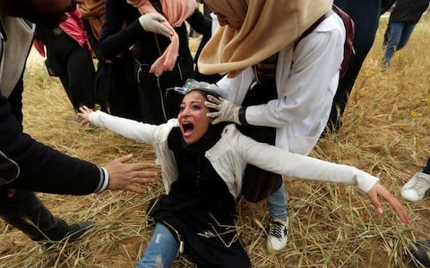 A Palestinian woman reacts after inhaling tear gas fired by Israeli forces - Credit: &nbsp;REUTERS