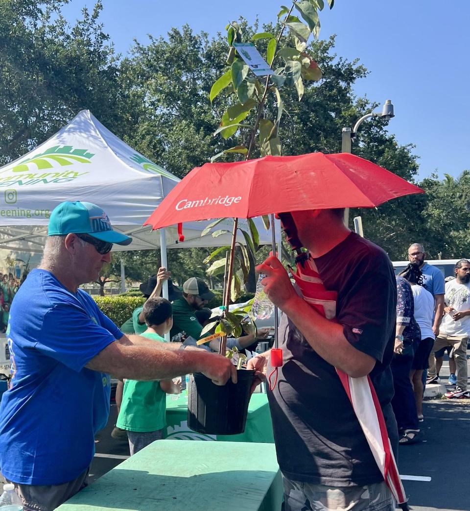 Niagara Bottling employee Andy Pisani (left) gives away a 3-gallon soursop fruit tree at a free tree event in Jupiter on Saturday, May 18, 2024 that was sponsored by Community Greening, Niagara Bottling and the Arbor Day Foundation.