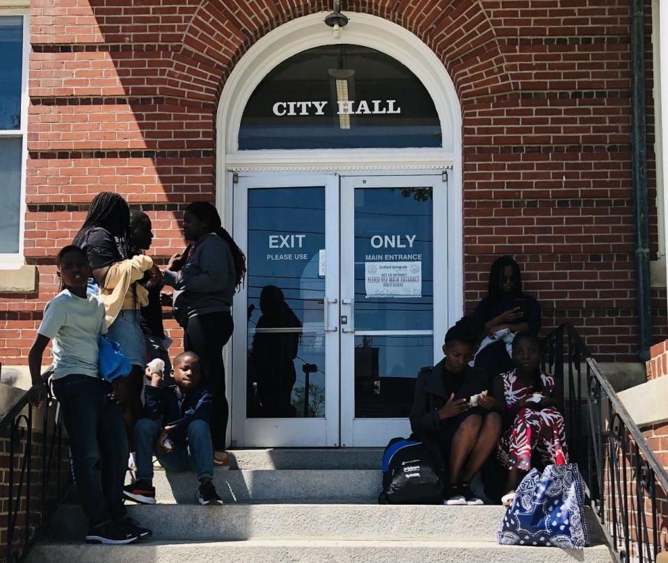 Asylum seekers wait to be helped outside Sanford City Hall in Sanford, Maine, on May 8, 2023.