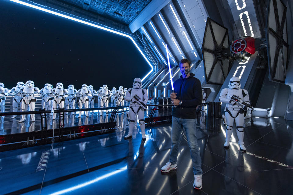 In this photo provided by Walt Disney World, NFL star Tom Brady visits Star Wars: Galaxy's Edge inside Disney's Hollywood Studios at Walt Disney World Resort in Lake Buena Vista, Fla., Monday, April 5, 2021. A mask-wearing Brady visited the Star Wars-themed section of Walt Disney World with his family and friends, two months after he led the Bucs to a Super Bowl win against the Chiefs. (Matt Stroshane/Disney World via AP)