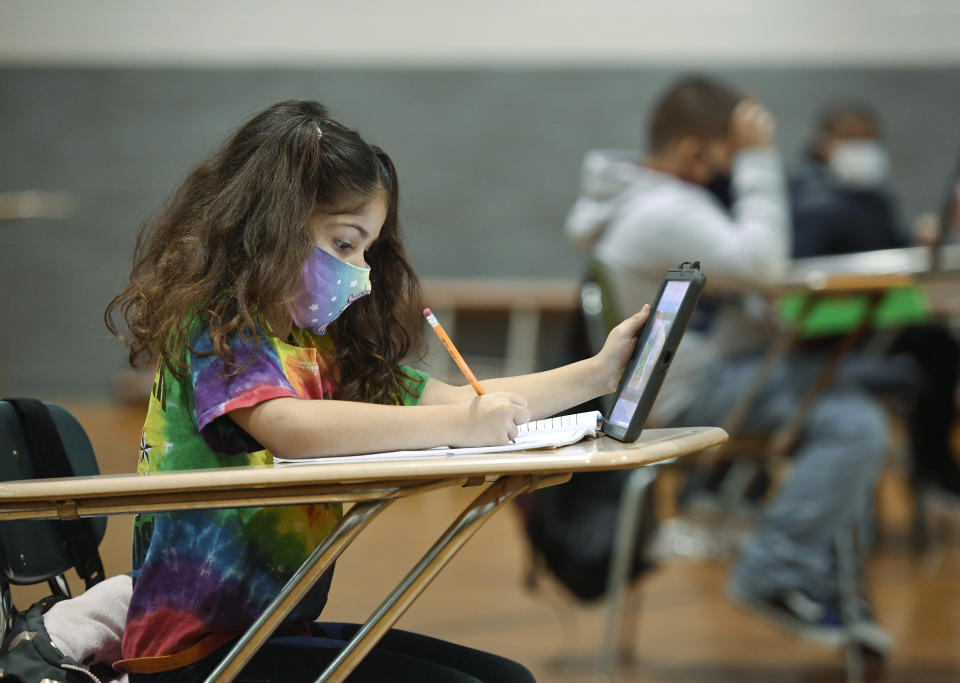 Christina Pagan, 7, does her school work using an iPad and a pencil with a workbook. (Credit: Ben Hasty/MediaNews Group/Reading Eagle via Getty Images)