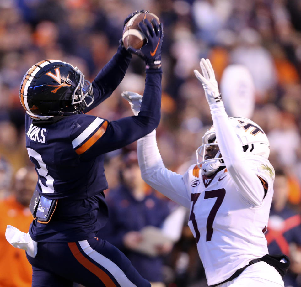 Virginia wide receiver Dontayvion Wicks (3) has a pass from quarterback Virginia quarterback Brennan Armstrong broken up by Virginia Tech defensive back Brion Murray (37) in the first half of an NCAA college football game in Charlottesville, Va. Saturday Nov. 27 2021. (Matt Gentry/The Roanoke Times via AP)