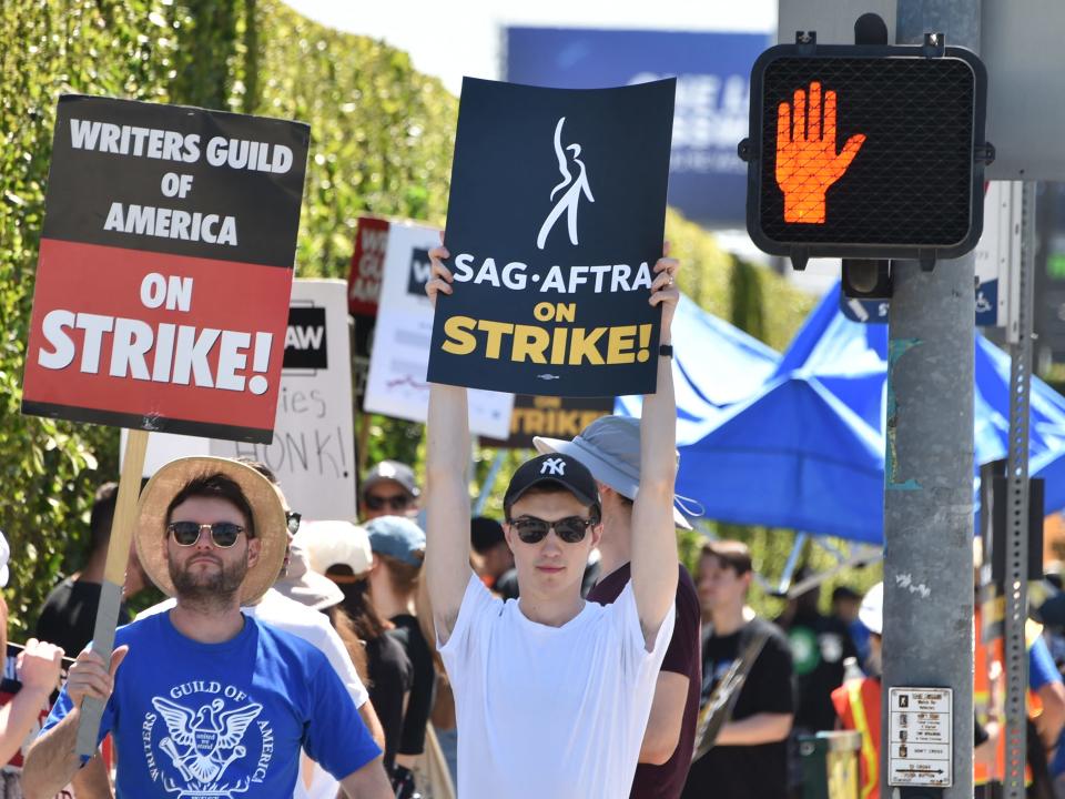 image of striking actors holding up picket signs in Hollywood