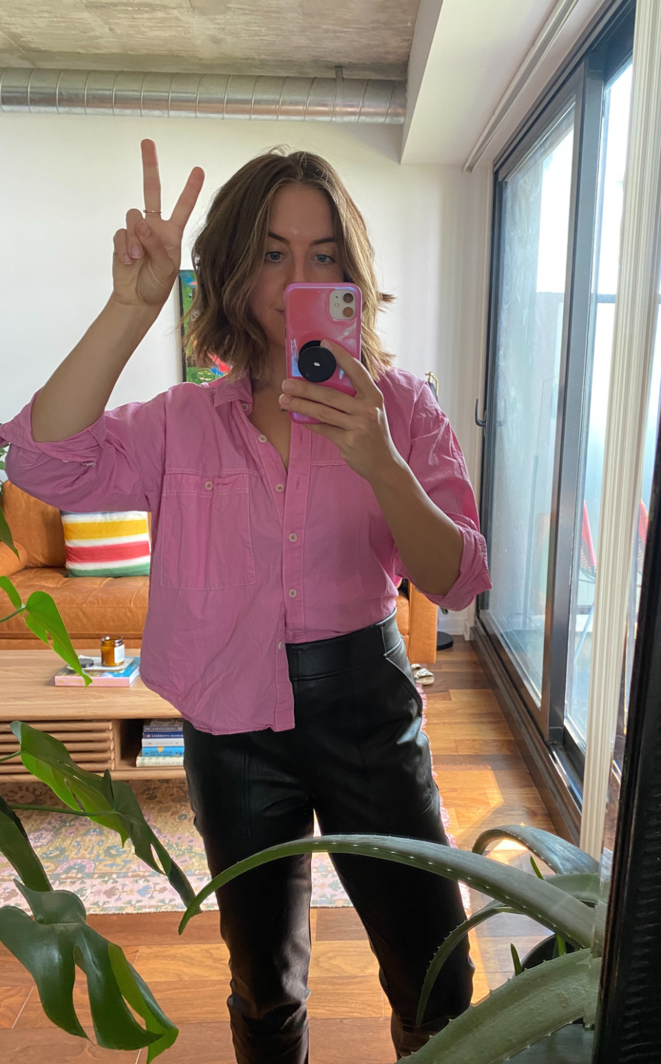 brunette woman wearing pink button-down shirt and black spanx faux leather joggers