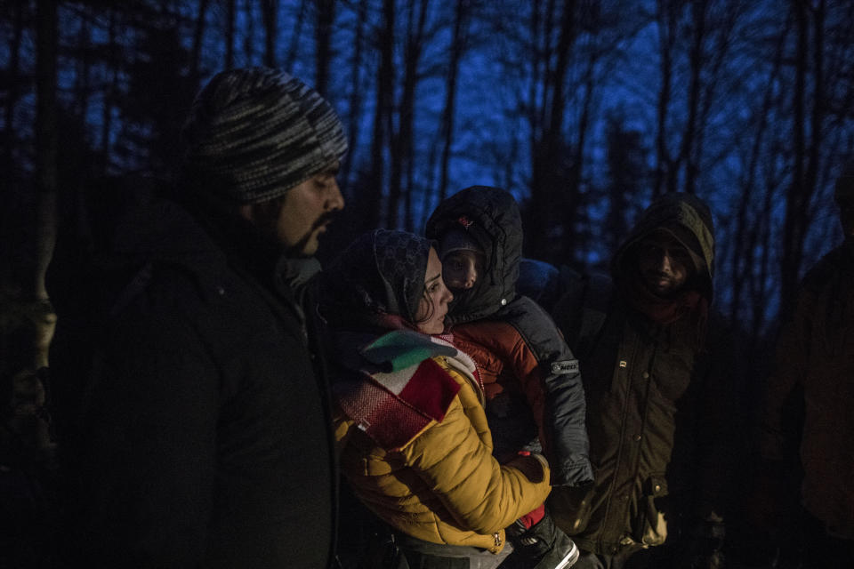 In this picture taken Thursday Dec. 12, 2019, Indian migrant Suhil, 23, helps Syrian migrant Fatma, 24, to hold her son Omar, 1, while crossing the mountains between Bosnia and Croatia near the town of Bihac, northwestern Bosnia. (AP Photo/Manu Brabo)