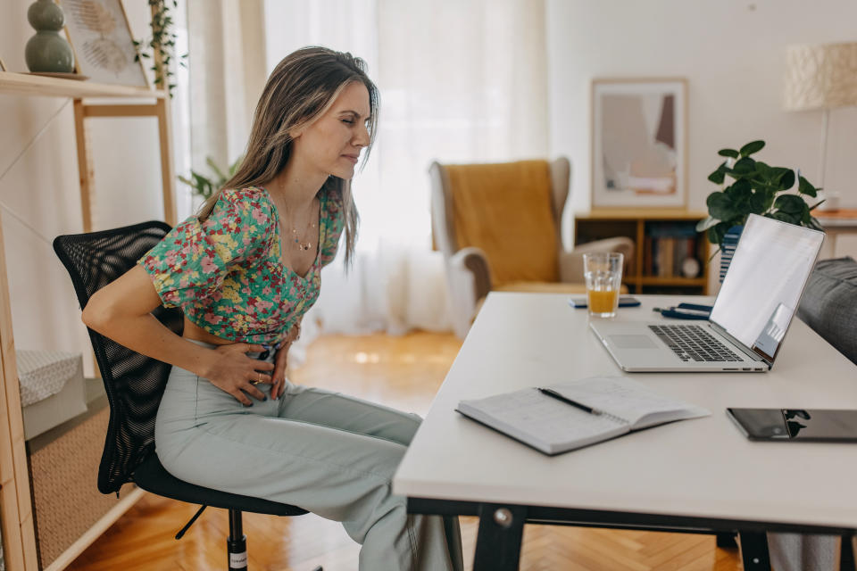 Woman holding her stomach at work. (Getty Images)