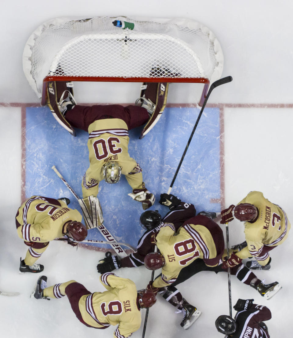 With the puck by Union's Daniel Carr's hand, Boston College's Thatcher Demko, center top, pokes it with his stick as Michael Sit (18), Ian McCoshen (3), Brendan Silk (9) and Michael Matheson (5) come to Demko's aid during the second period of an NCAA men's college hockey Frozen Four tournament game on Thursday, April 10, 2014, in Philadelphia. (AP Photo/Chris Szagola)
