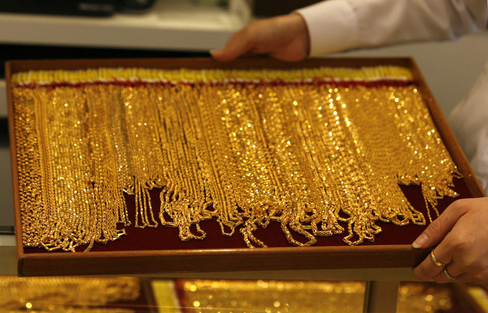 A shop attendant carries a tray of gold necklaces at a jewellery store in Singapore September 18, 2008. Gold reversed earlier gains to fall below $860 per ounce on Thursday, down about 0.4 percent from the previous day, as buying ran out of steam. It had earlier risen by more than 3 percent to $892.10, extending its biggest ever one-day rise in absolute dollar terms on Wednesday, when buyers flocked to the precious metal as a safe haven asset, and as a hedge against falling stocks.  REUTERS/Vivek Prakash (SINGAPORE)