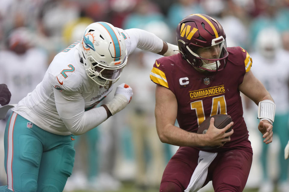 Washington Commanders quarterback Sam Howell (14) avoids Miami Dolphins linebacker Bradley Chubb (2) before running for a touchdown during the second half of an NFL football game Sunday, Dec. 3, 2023, in Landover, Md. (AP Photo/Mark Schiefelbein)