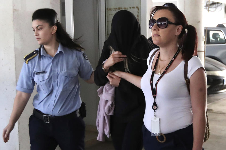 Police officers escort a 19-year-old British woman, center, from the Famagusta court in town of Paralimni, Cyprus, Monday, July 29, 2019. The 19-year-old British woman has been arrested on suspicion of filing a false complaint of gang rape for which a dozen Israeli teens were held, Cyprus police say. (AP Photo/Petros Karadjias)