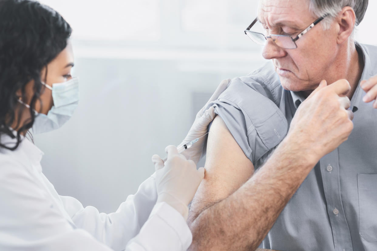 Flu Vaccine. Close up of young latina nurse giving elderly male patient injection in hospital room, copyspace