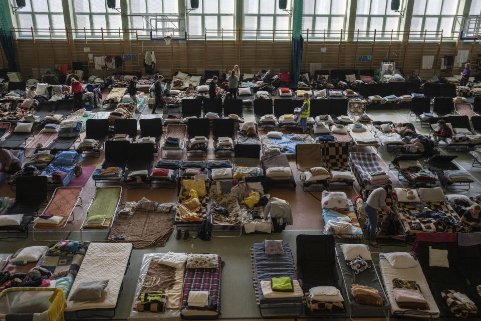 FILE - People who fled the war in Ukraine rest inside an indoor sports stadium being used as a refugee center, in the village of Medyka, a border crossing between Poland and Ukraine, on March 15, 2022. The U.N. refugee agency says more than 4 million refugees have now fled Ukraine following Russia’s invasion, a new milestone in the largest refugee crisis in Europe since World War II. (AP Photo/Petros Giannakouris)