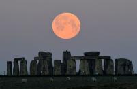FILE PHOTO: The full moon, known as the "Super Pink Moon", sets behind Stonehenge stone circle near Amesbury