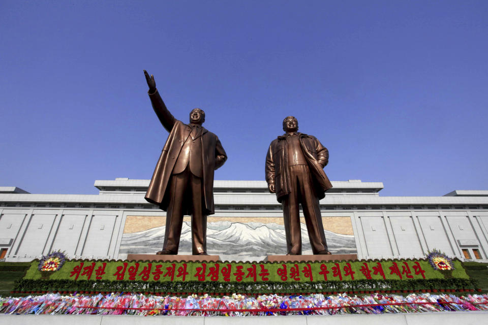 FILE - Flowers are laid under bronze statues of North Korea's late leaders Kim Il Sung, left, and Kim Jong Il at Mansu Hill in Pyongyang, North Korea, Friday, April 15, 2016, to commemorate North founder Kim Il Sung's birthday. The banner reads: "Great comrades Kim Il Sung and Kim Jong Il are with us eternally." (AP Photo/Kim Gwang Hyon, File)