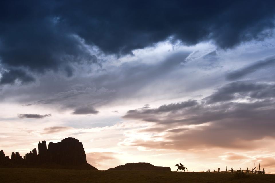 Jim Krantz's "Epic Western No. 7" shows, from far away, a silhouette of a horse and rider amid rock formations.