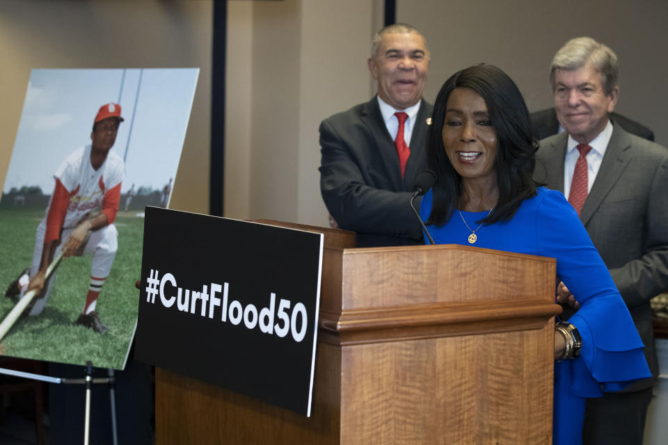 Rep. William Lacy Clay, D-Mo., left, and Sen. Roy Blunt, R-Mo., right, stand as Judy Pace Flood speaks during a news conference as they call for the late Curt Flood to be inducted into the Baseball Hall of Fame, on Capitol Hill, Thursday, Feb. 27, 2020 in Washington. (AP Photo/Alex Brandon)