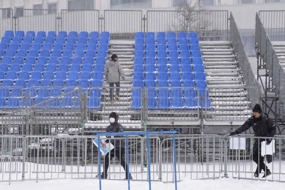 Event staff remove signage from the venue after it was announced that the men's slalom race has been cancelled due to weather conditions during the FIS Alpine Ski World Cup at Naeba Ski Resort in Yuzawa, Niigata prefecture, northern Japan, Sunday, Feb. 23, 2020. (AP Photo/Christopher Jue)