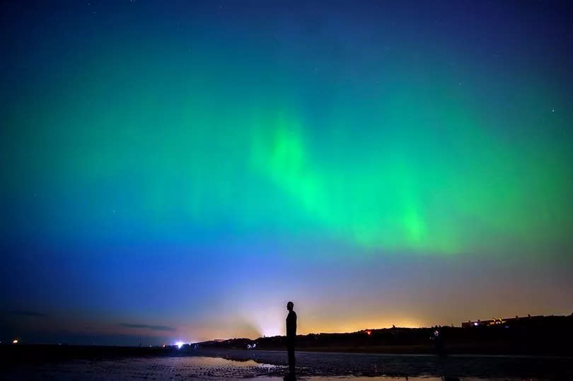 The aurora borealis, also known as the northern lights, glow on the horizon at Another Place by Anthony Gormley, Crosby Beach, Liverpool , Merseyside . Picture date: Friday May 10, 2024