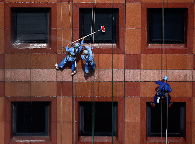 Window cleaners hang from the facade of Ngee Ann city mall in Singapore January 9, 2014. (Reuters/Petar Kujundzic)