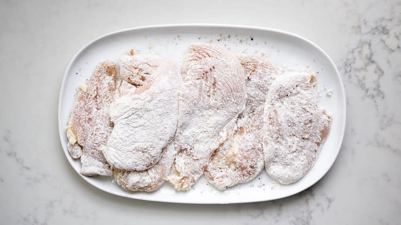 floured raw chicken on plate