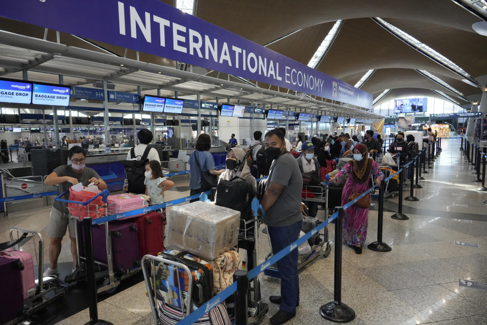 Travelers line up at check in counter at Kuala Lumpur International Airport in Sepang, Malaysia, Friday, April 1, 2022. Malaysia's international borders open to foreigners on April 1 and fully vaccinated travelers do not have to undergo quarantine. (AP Photo/Vincent Thian)