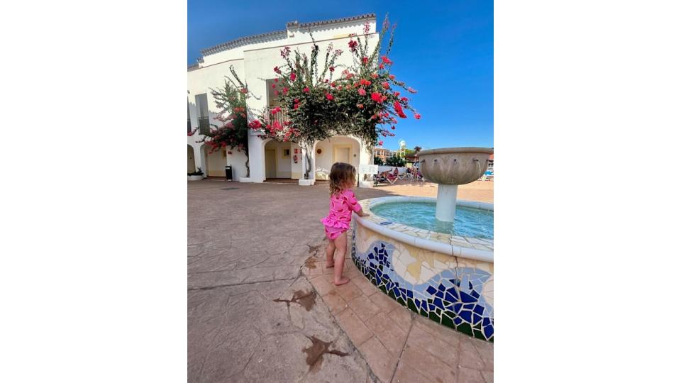 young girl standing by water fountain