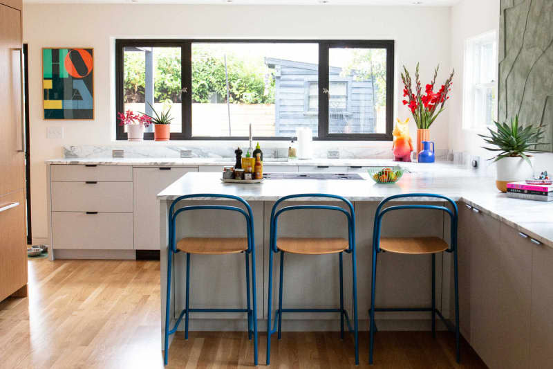 Blue stools under marble counter ledge in white kitchen.