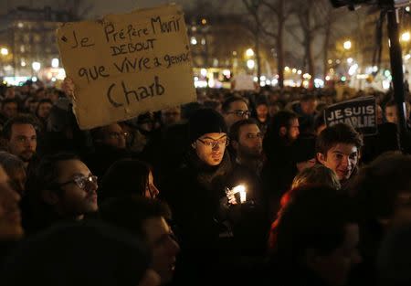 A man holds a placard that reads, "I prefer to die standing than live on my knees", during a vigil to pay tribute to the victims of a shooting by gunmen at the offices of weekly satirical magazine Charlie Hebdo in Paris at Republique square January 7, 2015. REUTERS/Youssef Boudlal