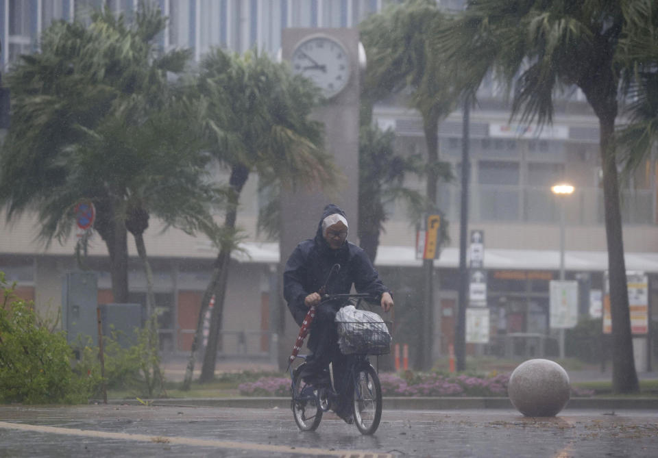 A man on a bicycle makes his way through the rain in Miyazaki, southern Japan, Sunday, Sept. 18, 2022, as a powerful typhoon approaching southern Japan on Sunday lashed the region with strong winds and heavy rain.(Kyodo News via AP)