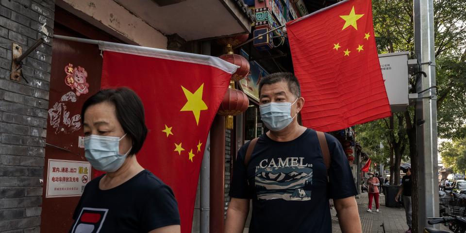 Pedestrians walk by China's national flag in Beijing.