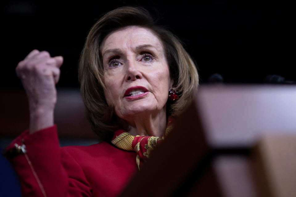 House Speaker Nancy Pelosi holds up her right fist as she speaks during her weekly news conference. 