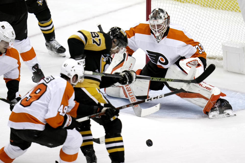 Pittsburgh Penguins' Sidney Crosby (87) can't get off a shot in front of Philadelphia Flyers goaltender Samuel Ersson (33) with Noah Cates (49) defending during the first period of an NHL hockey game in Pittsburgh, Sunday, April 2, 2023. (AP Photo/Gene J. Puskar)