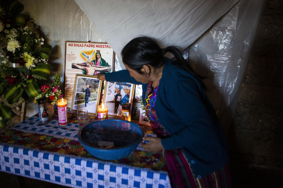 Natalia Tomas places a photo of her son on an altar in her home in in Comitancillo, Guatemala, Wednesday, Jan. 27, 2021. She believes that her son is one of the charred corpses found in a northern Mexico border state on Saturday. The country's Foreign Ministry said it was collecting DNA samples from a dozen relatives to see if there was a match with any of the bodies. (AP Photo/Oliver de Ros)