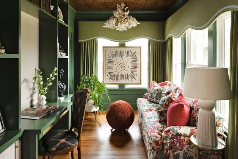 Floral sofa in green painted sitting room.