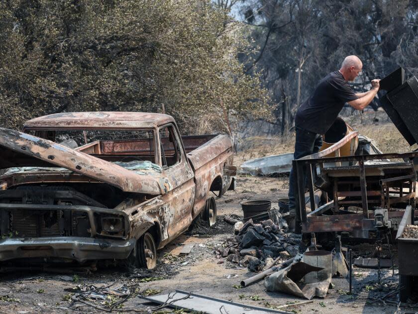 Sean Rains inspects his shaker table next to the rubble of his home and a burned pickup truck.