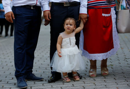 A Roma family with a baby girl stands in front of the chapel in Csatka, Hungary on September 9, 2017. REUTERS/Laszlo Balogh