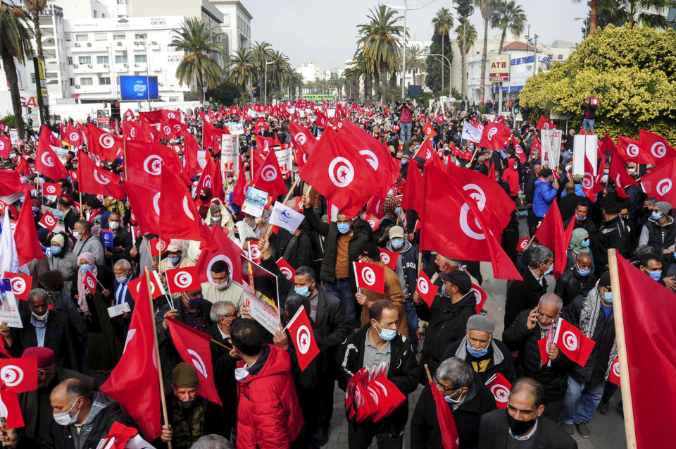 Supporters of the islamist Ennada party march with Tunisian flags during a rally in Tunis, Tunisia, Saturday, Feb. 27, 2021. The party, Ennahdha, led by House Speaker Rached Ghannouchi, has backed Prime Minister Hichem Mechichi in his standoff with President Kais Saied over a cabinet reshuffle. (AP Photo/Hassene Dridi)