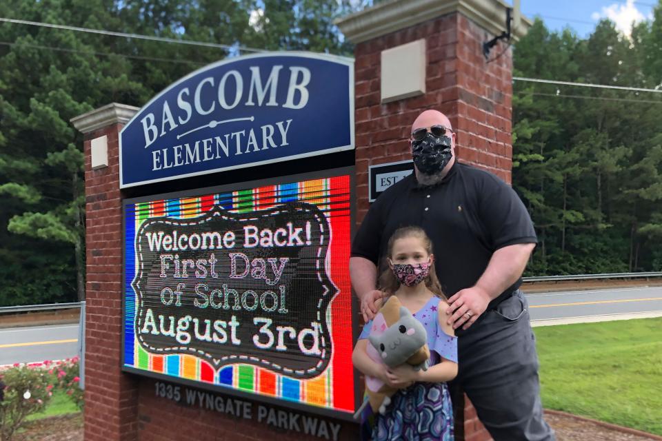 John Barrett and his daughter Autumn pose for photos outside Bascomb Elementary School in Woodstock, Ga., Thursday, July 23, 2020. Barrett says he will educate his daughter virtually and keep her out of in-person classes in Cherokee County schools, even though he's worried she will fall behind on her special education plans, because of concerns about COVID-19's spread.