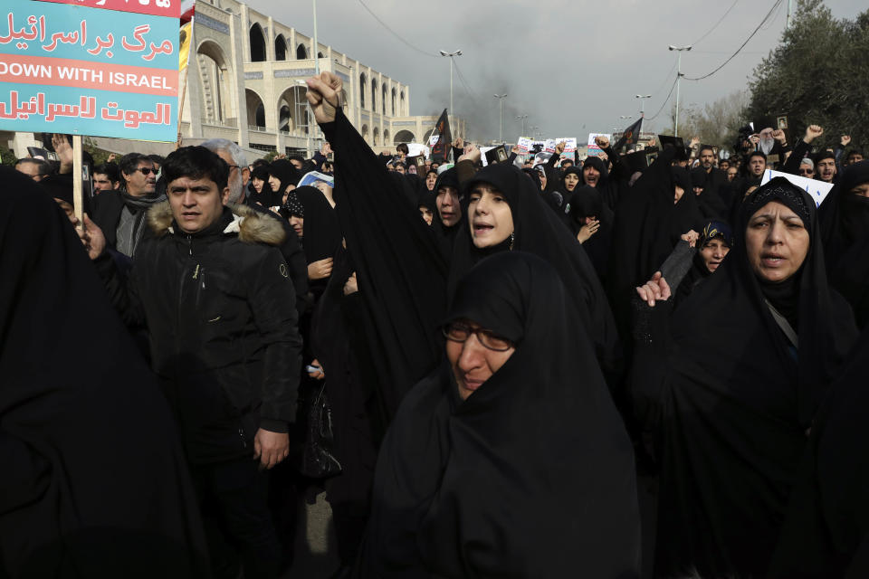 A woman clenches her fist as she chants slogan while a man holds an anti-Israeli placard during a demonstration over the U.S. airstrike in Iraq that killed Iranian Revolutionary Guard Gen. Qassem Soleimani in Tehran, Iran, Jan. 3, 2020. Iran has vowed 