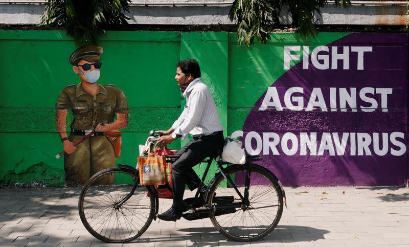 A man cycles past a graffiti covered wall amidst the spread of the coronavirus disease (COVID-19) on a street in Navi Mumbai