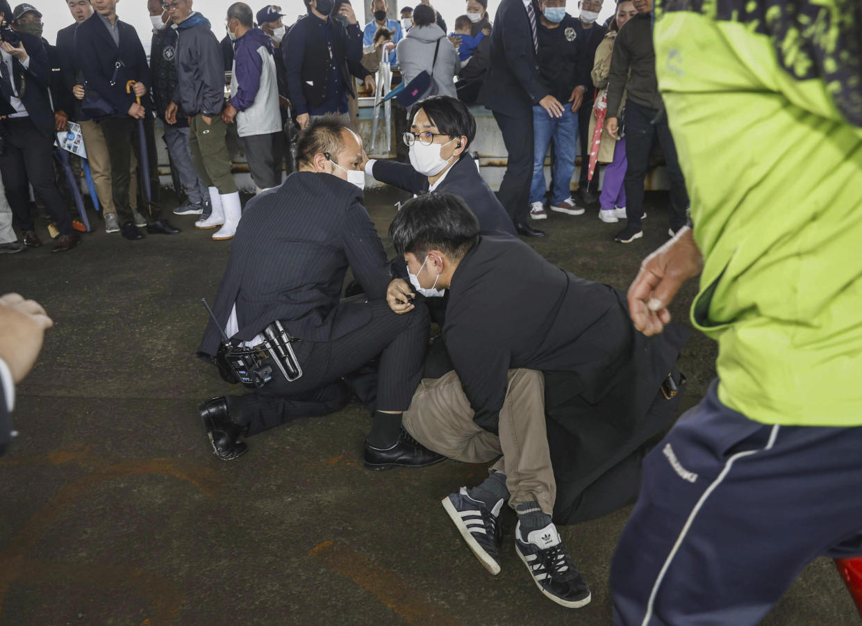 A man, on the ground, who threw what appeared to be a smoke bomb, is caught at a port in Wakayama, western Japan Saturday, April 15, 2023. Japan’s NHK television reported Saturday that a loud explosion occurred at the western Japanese port during Prime Minister Fumio Kishida’s visit, but there were no injuries. (Kyodo News via AP)