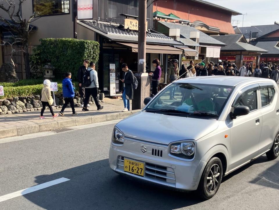 A Suzuki Alto on a busy road in Japan