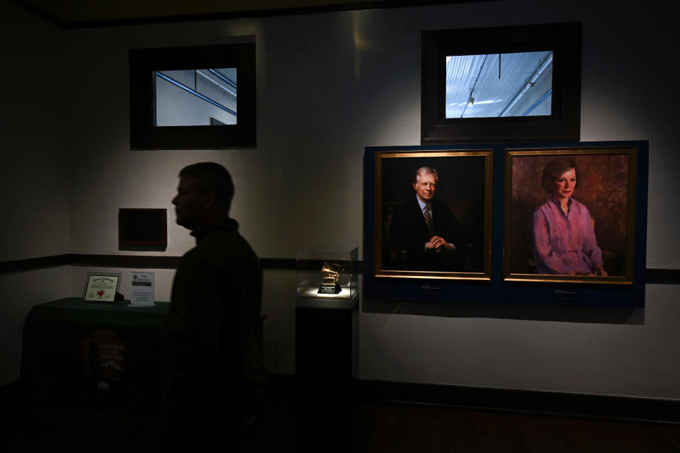 A visitor walks by portraits of former president Jimmy Carter and former first lady Rosalynn Carter in February at the Jimmy Carter National Historical Park Visitor Center in Plains, Ga. 