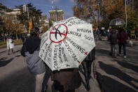A demonstrator holds an umbrella with messages against the privatisation of the health system during a protest in Madrid, Spain, Sunday, Nov. 29, 2020. The organizers delivered a manifesto to the Madrid regional authorities demanding the end privatization of the health system. (AP Photo/Bernat Armangue)