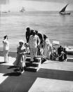 FILE - In this file photo dated Feb. 26, 1961, Britain's Queen Elizabeth II steps ashore at Bombay, India, for a visit to the atomic energy plant at the "Gateway to India," which King George V called "the jewel of the British crown" during his 1911 visit. Prince Philip who is accompanying the Queen on the state tour, can be seen nearing top of the Gangplank hat in hand. Prince Philip who died Friday April 9, 2021, aged 99, lived through a tumultuous century of war and upheavals, but he helped forge a period of stability for the British monarchy under his wife, Queen Elizabeth II. Philip helped create the Commonwealth of nations, with the queen at its head, in an attempt to bind Britain and its former colonies together on a more equal footing. (AP Photo, FILE)